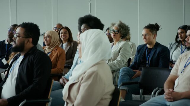 Multicultural audience actively participates in a professional seminar, attentively listening to a speaker. Ideal for business, education, and corporate event themes.