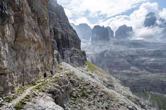 Two mountaineers on a hiking trail in front of a picturesque mountain landscape with rocky peaks, Via Ferrata SOSAT via ferrata, summit of Cima Tosa in the back, Brenta Mountains, Trentino, Italy