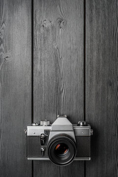 Analog film SLR camera placed flat on a textured gray wood surface. Copy space.