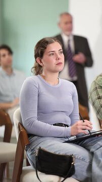 Young female student listens attentively to a lecture, taking notes against the background of the teacher. University student prepares for exams. High quality 4k footage