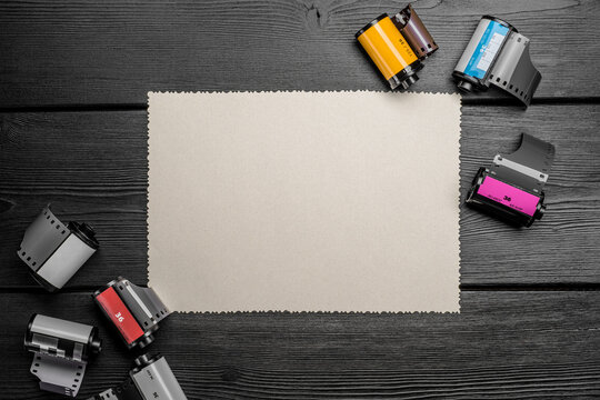 Vintage camera film rolls and blank print paper on wood