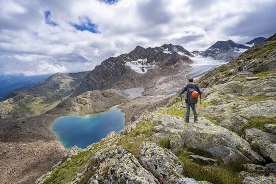 Mountaineer in front of dramatic high mountain landscape, view of mountain lake Vogelh&uuml;ttensee and glacier &Uuml;beltalferner, Stubai Alps, South Tyrol, Italy