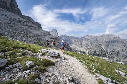 Three mountaineers on a hiking trail, rocky mountain landscape, Via Ferrata SOSAT via ferrata, Brenta Mountains, Trentino, Italy