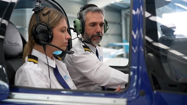 Pilot instructor training a female student in a helicopter cockpit
