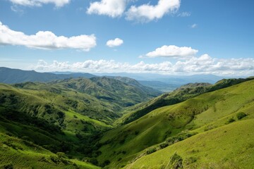 Fototapeta premium The hills rolling into a green valley beneath a bright blue sky with clouds