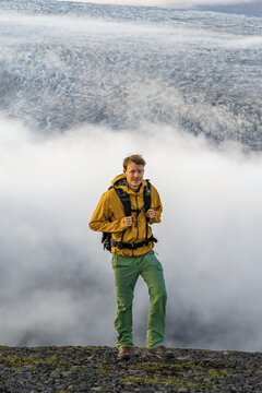Young man in front of impressive landscape at sunset, fog, clouds moving around, glacier ice of the glacier tongue K&ouml;tluj&ouml;kull, glacier Myrdalsj&ouml;kull, Pakgil, Iceland