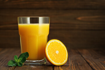 Fototapeta premium Orange juice in glass with mint and half citrus fruit on rustic wooden table