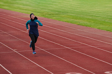 Fototapeta premium Female Athlete Running on Outdoor Track Wearing Sportswear and Headscarf During Training Session