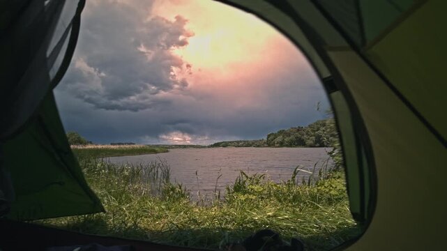 Dramatic stormy sky timelapse over river Kyiv region Ukraine. View from inside camping tent door. Fast moving dark thunderstorm clouds, rain approaching, strong wind blowing, waves on water.Adventure.