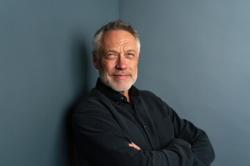 Obraz premium The man with folded arms posing confidently against a blue studio background
