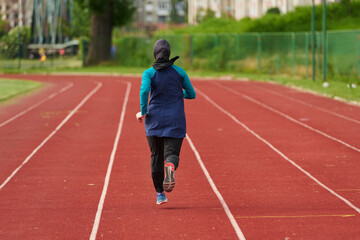 Fototapeta premium Woman Running on Outdoor Track in Headscarf Training for Fitness and Endurance