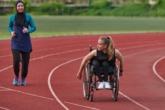 Female Wheelchair Athlete Training on Outdoor Running Track With Friend Jogging Beside Her