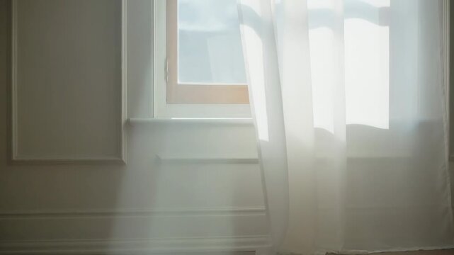 Shifting sheer white curtain and window frame exposing window in room, draft softening sun patches