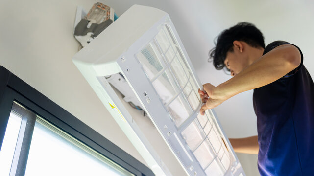 Repairman cleaning air conditioner filters in modern home, Maintenance service worker removing air conditioner filter for cleaning, Technician man installing indoor air conditioner unit on wall