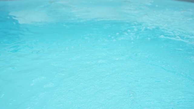 Calming turquoise pool water surface rippling with small waves and bubbles, creating a serene and refreshing background perfect for relaxation and summer vacation concepts