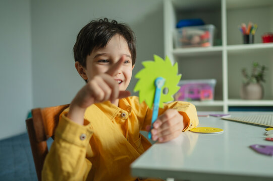 Child learning mechanics with a gear toy at a desk indoors