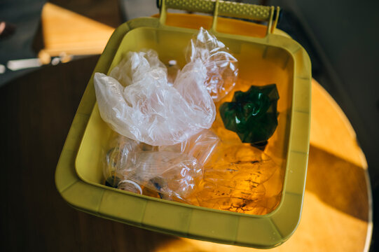 Yellow recycling bin filled with crushed plastic bottles indoors