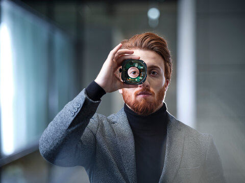 Portrait of businessman looking through an object in modern office