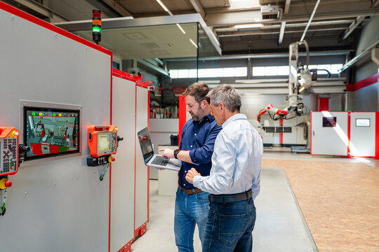 Employees planning with laptop in modern automation factory