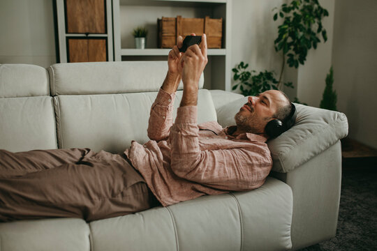 Man lying down and watching movie on smart phone at home