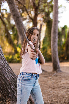 Explorer aiming a wooden slingshot with a pinecone in nature