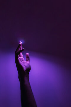 Human hand under purple neon lighting