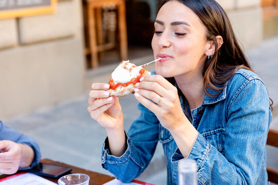 Smiling woman eating pizza at sidewalk cafe