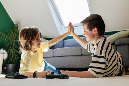 Children give high five while playing video game at home