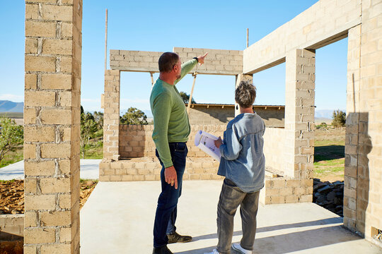 Builder and architect discussing blueprint at building site