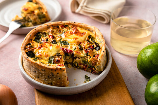 Studio shot of freshly baked zucchini quiche with red bell pepper and onion