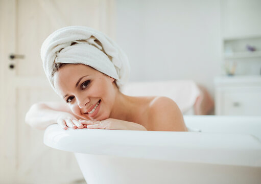 Portrait of smiling woman with towel around her head taking a bath at home