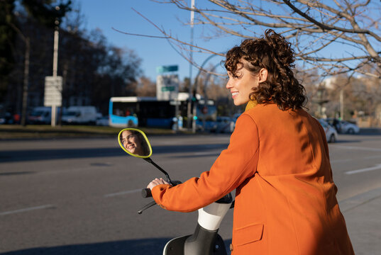 Smiling woman with electric scooter on road
