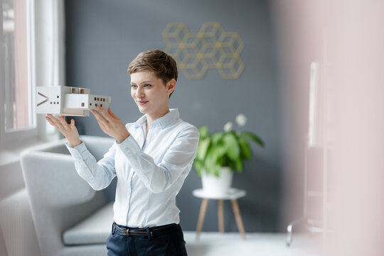 Confident businesswoman holding architectural model in office