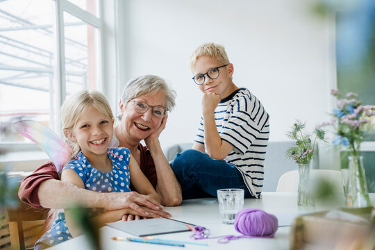 Smiling grandmother and grandchildren playing at home indoors