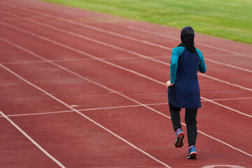 Fototapeta premium Female Muslim Athlete Running On Outdoor Track Wearing Hijab And Modest Sportswear For Fitness