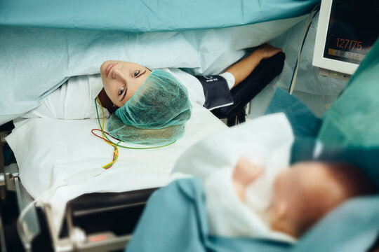 Operating room nurse bringing baby to mother after c-section