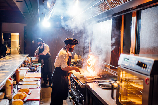 Chefs wearing protective face masks preparing a dish in restaurant kitchen