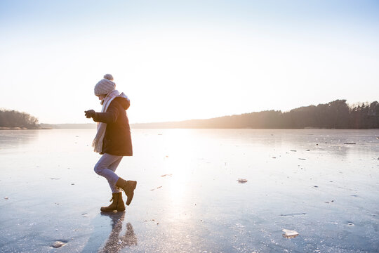 Germany, Brandenburg, Lake Straussee, girl walking on frozen lake