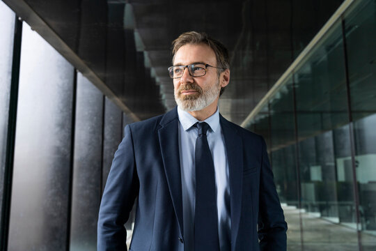 Businessman in suit wearing eyeglasses standing in corridor