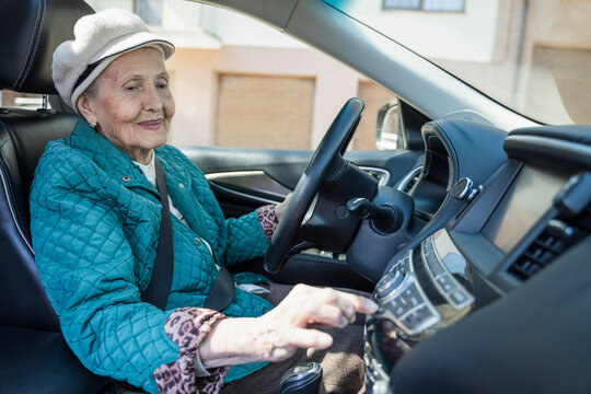 Smiling senior woman playing music on car stereo