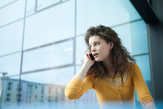 Frightened young woman on the phone at the window