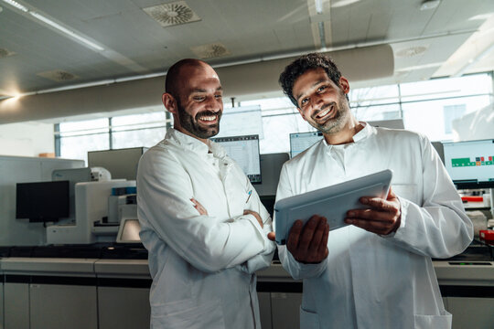 Team of scientists evaluating research on a tablet in laboratory
