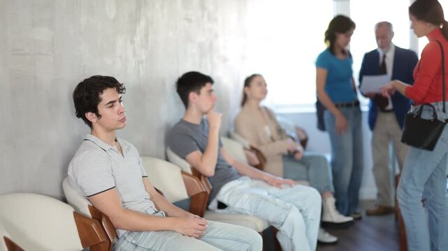 Group of students sit in line to do an internship and get a job in a company, they communicate with a qualified manager. Students before taking exams
