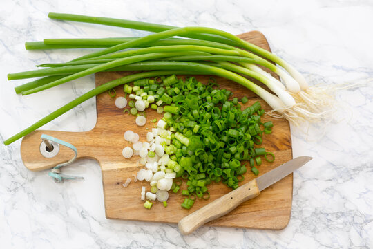 Chopped and whole spring onions on wooden board