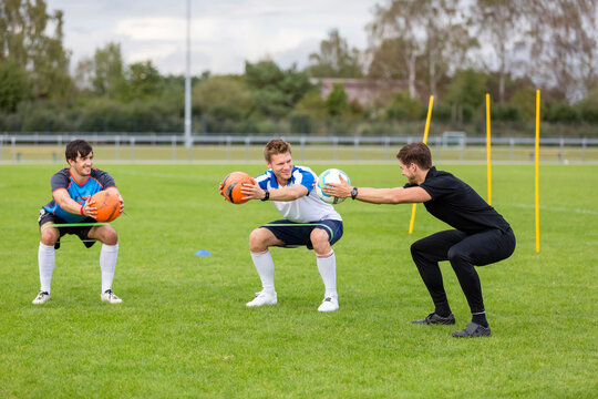 Coach exercising with soccer players on sports field