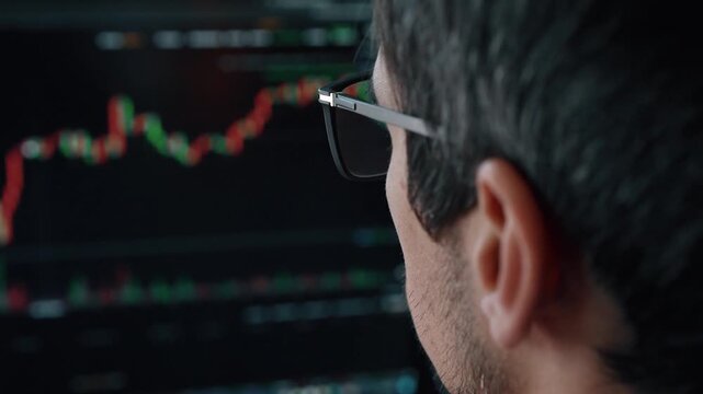 trader investor man using laptop computer for real time stock market monitoring with candlestick digital chart in modern tech setup. trade app Website with crypto graphs on screen. monitors financial