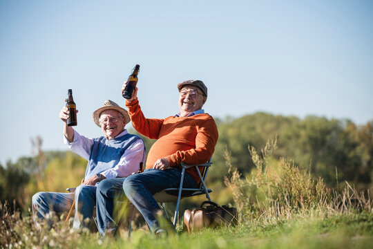 Two old friends sitting in the fields, drinking beer, talking about old times