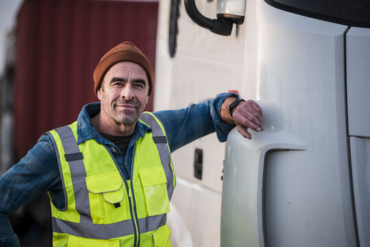 Mature male driver standing by truck at dock