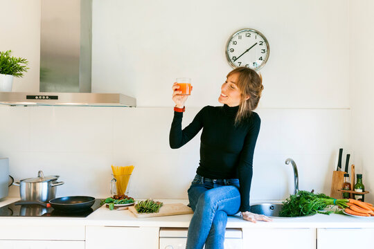 Young woman drinking fresh grapefruit juice in her kitchen