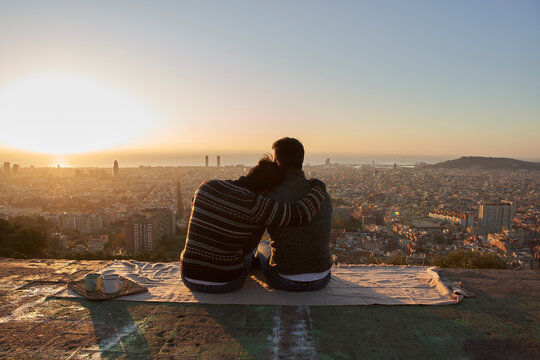 Gay boyfriends looking at cityscape against clear sky while sitting on observation point, Bunkers del Carmel, Barcelona, Spain